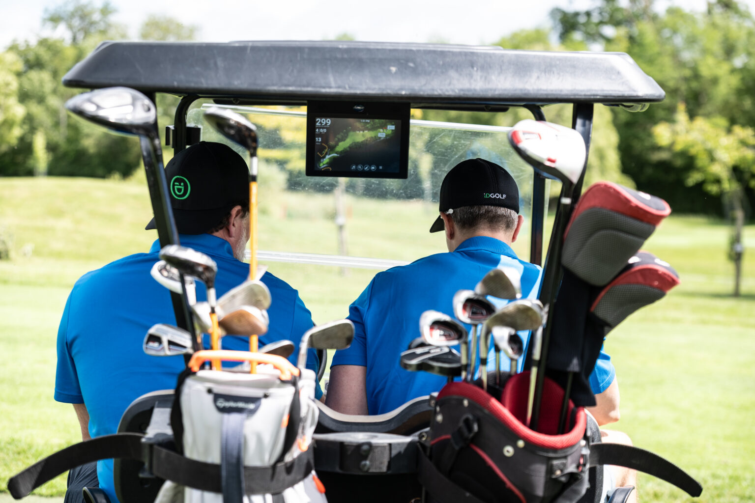 Golfers heading out in a buggy loaded with clubs