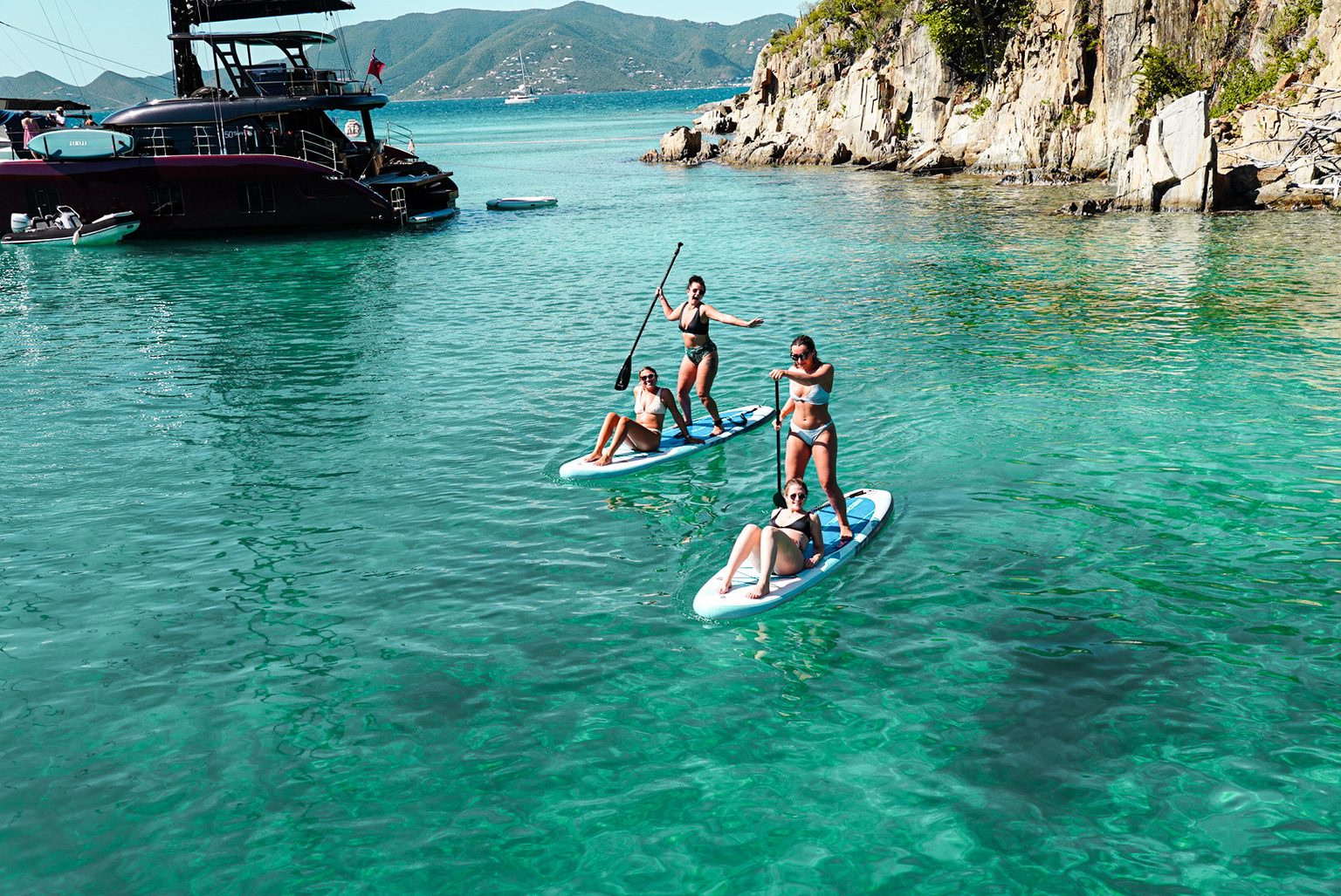 Guests paddleboarding in a clear turquoise cove