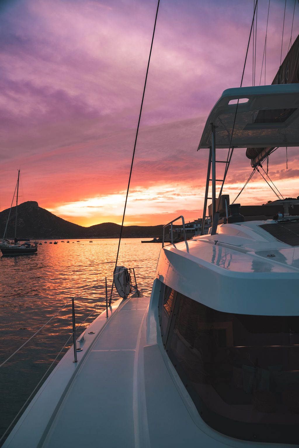 Sunset over an anchorage seen from a catamaran side deck